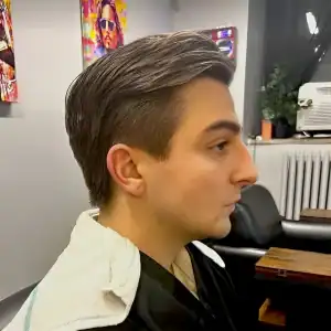A young businessman with a professional slicked-back haircut and a short fade on the sides, showcasing a modern corporate style from MadMen Haircuts in Midtown Manhattan.