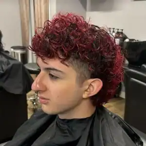 young male client with a curly haircut and red highlights on top, expertly faded on the sides to a number one clip by a stylist at MadMen Haircuts in Midtown Manhattan.
