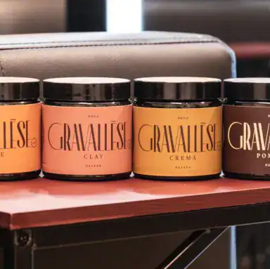 Multiple containers of Gravaliese, a popular men's hair product, all lined up on a shelf at MadMen Haircuts.