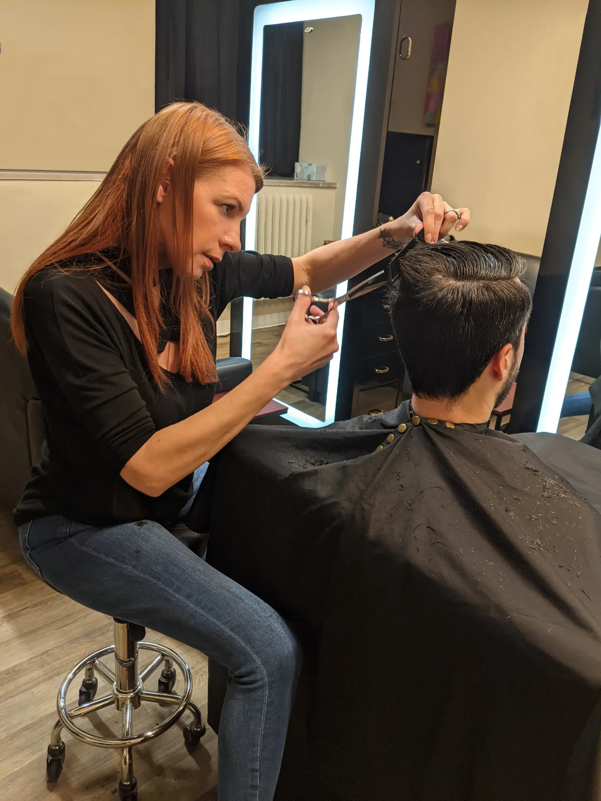 A close-up shot of a skilled female stylist at MadMen Haircuts using precision scissors to cut a male client's hair, highlighting the meticulous craftsmanship of our team in Midtown Manhattan.